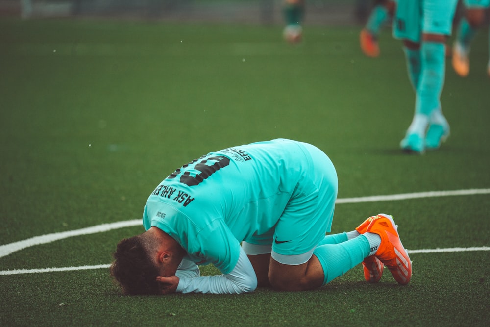 a soccer player with his head down on the ground