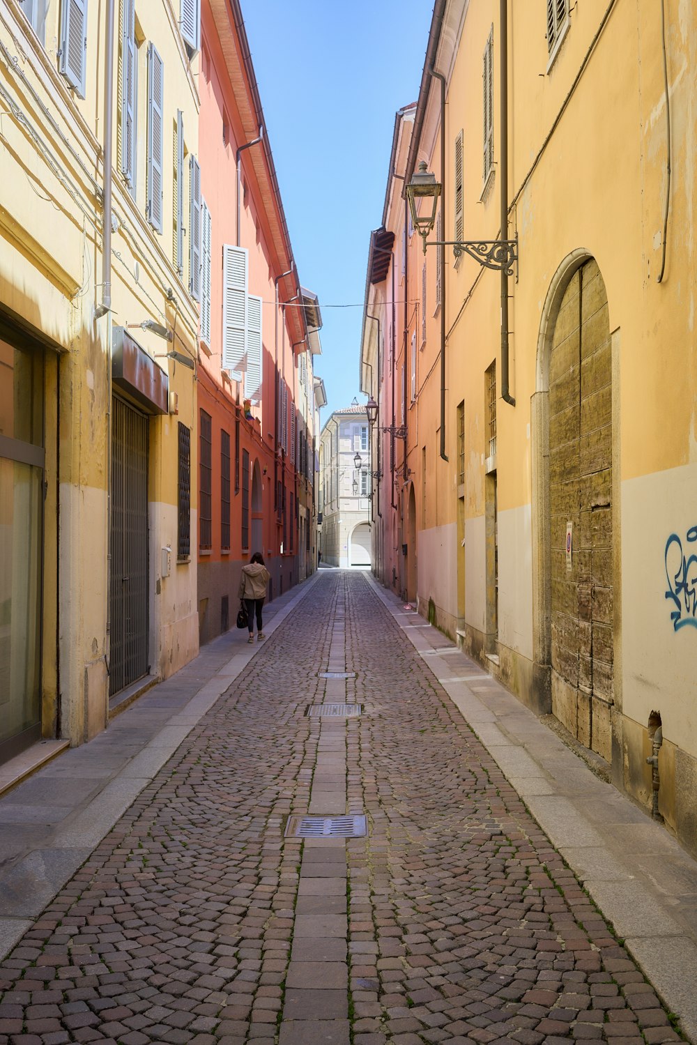a cobblestone street with a person walking down it