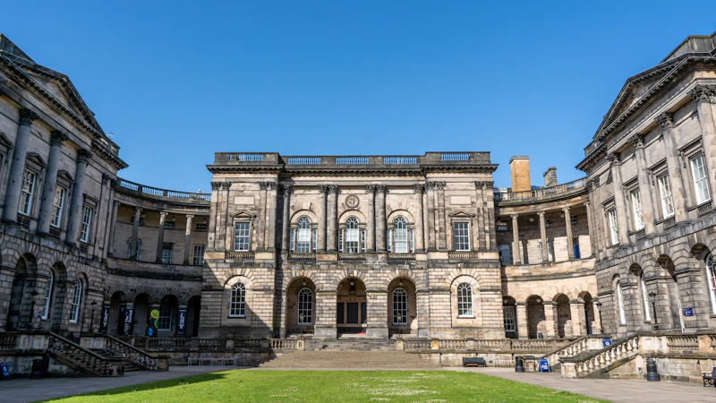 Historic building behind a green lawn in Edinburgh, Scotland