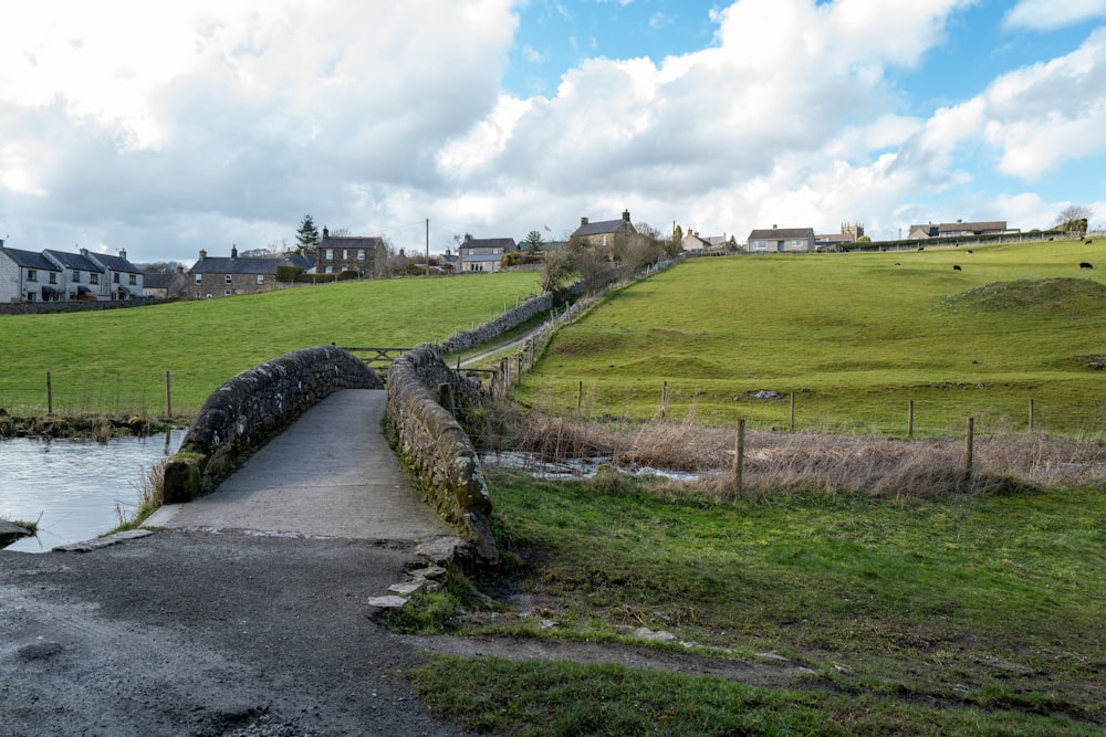 a stone bridge over a stream in a green field