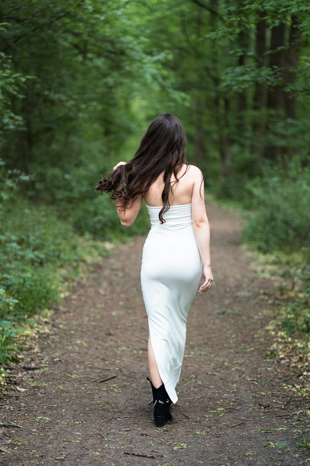 a woman in a white dress walking down a path