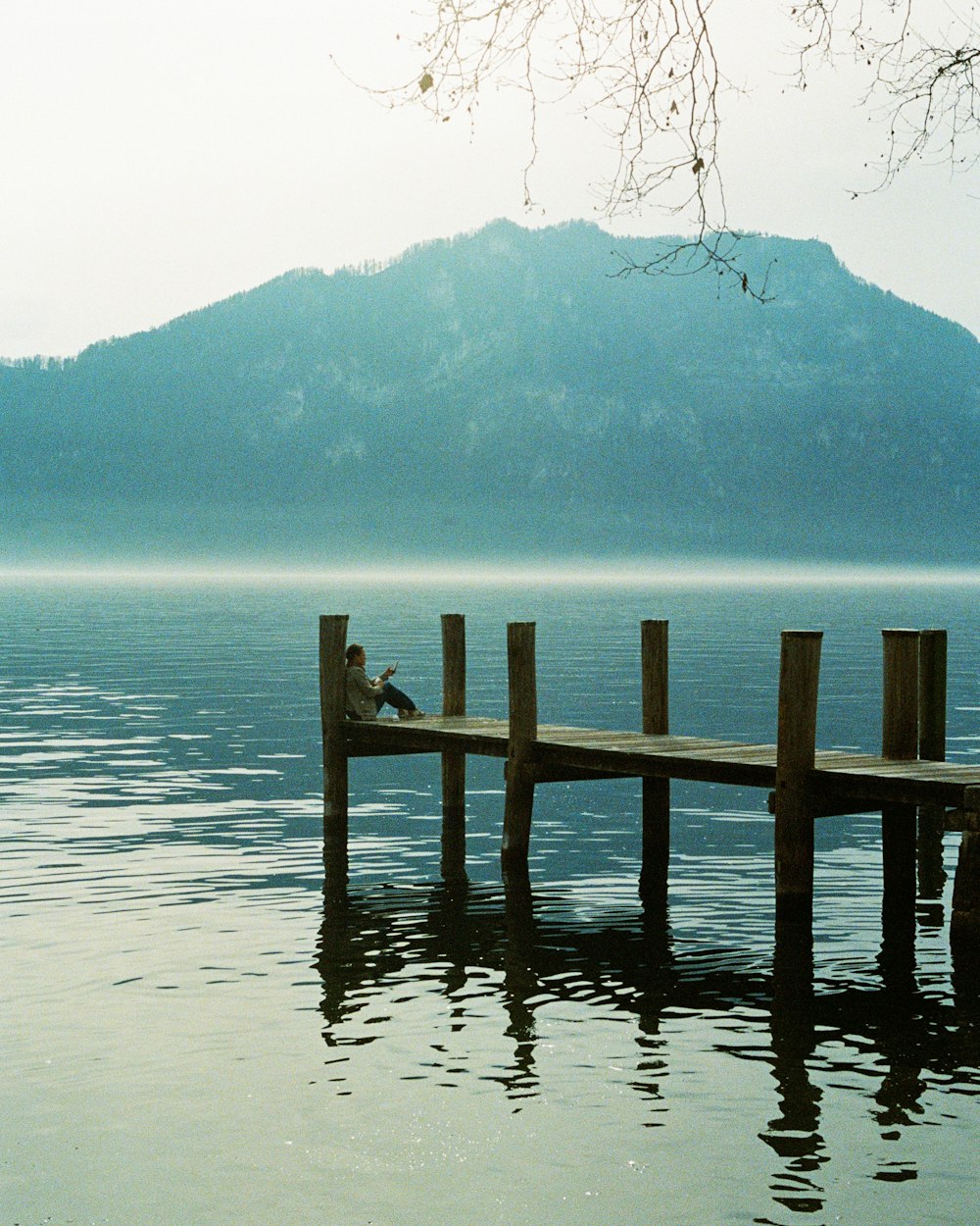 a person sitting on a dock in the middle of a lake