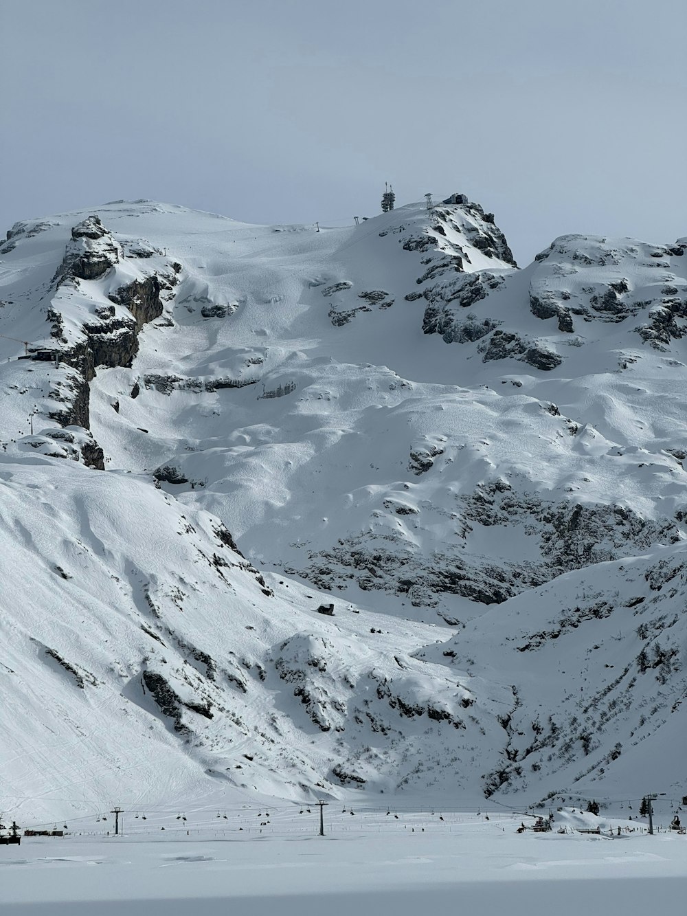 a snow covered mountain with a ski lift in the distance