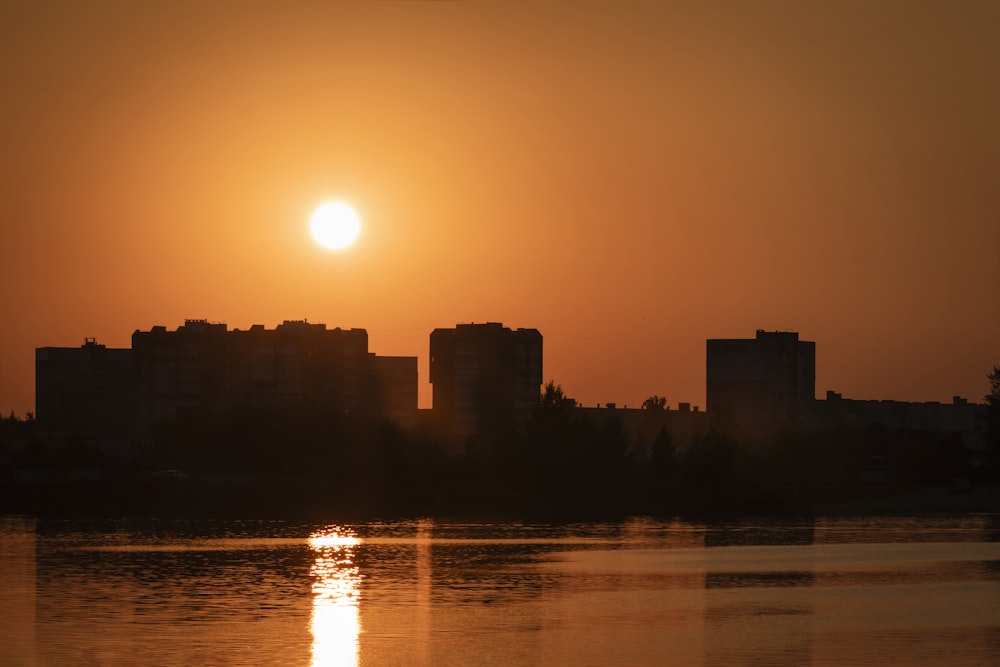 the sun is setting over a city and a body of water