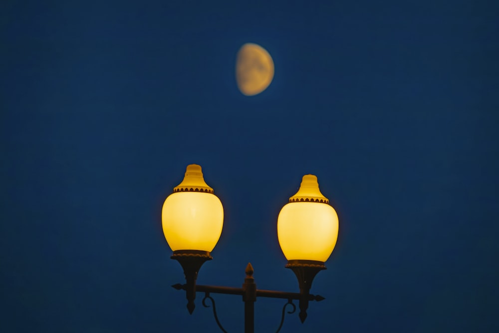 a street light with a half moon in the background