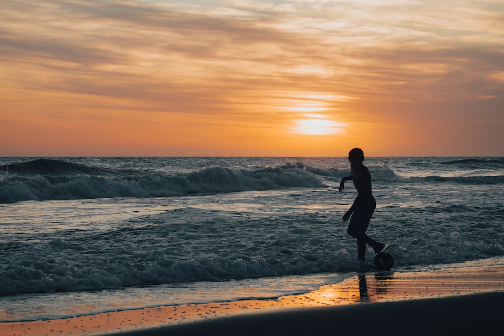 a person walking on the beach at sunset