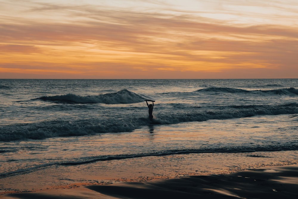 a person standing in the ocean at sunset