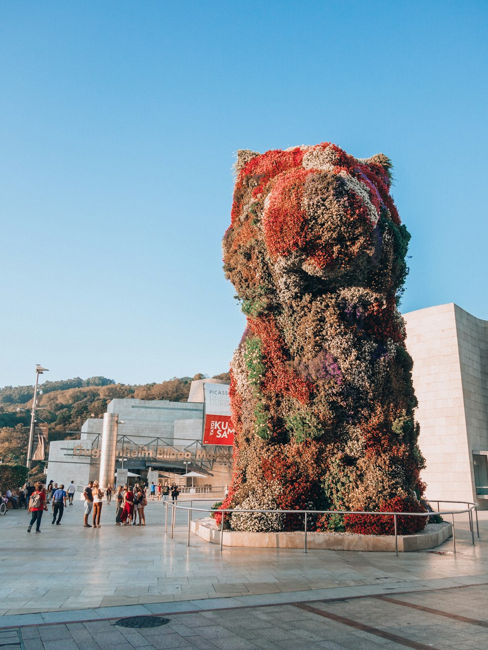 a giant bear made out of flowers in a plaza