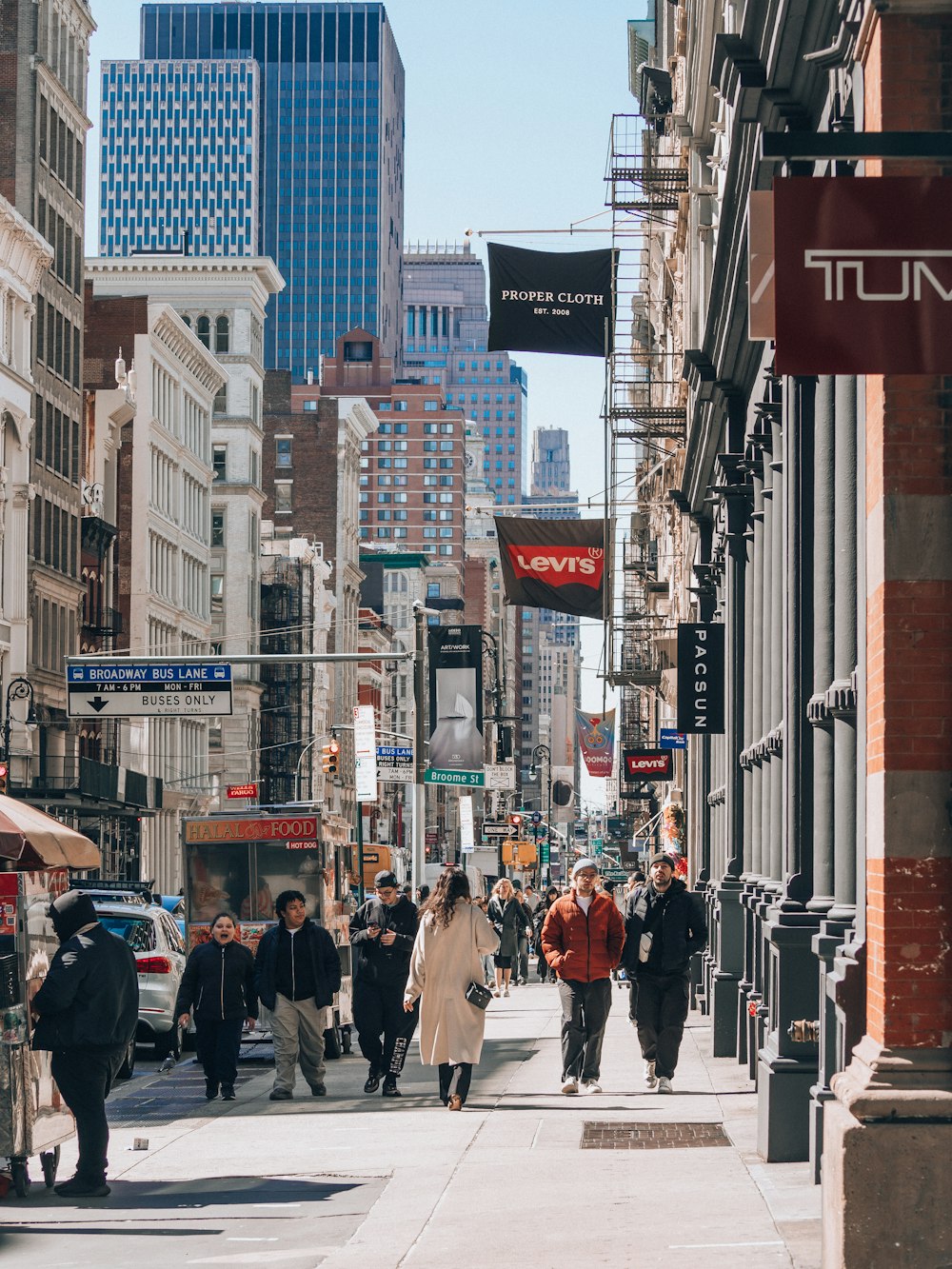 a group of people walking down a street next to tall buildings