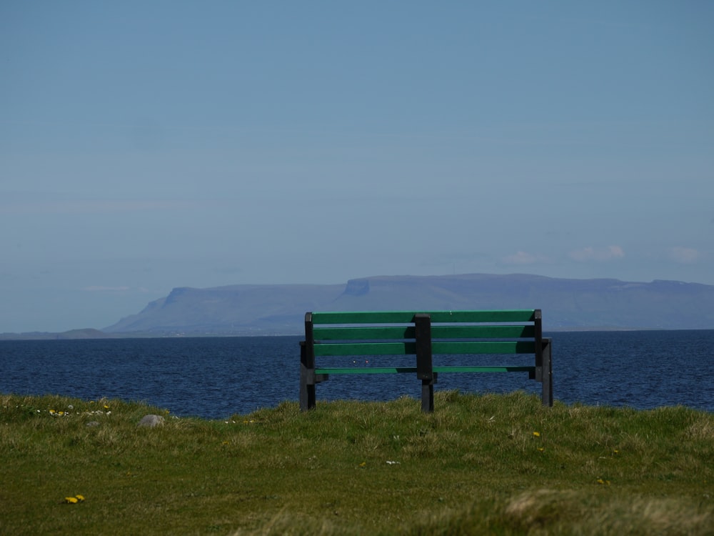 a green bench sitting on top of a lush green field