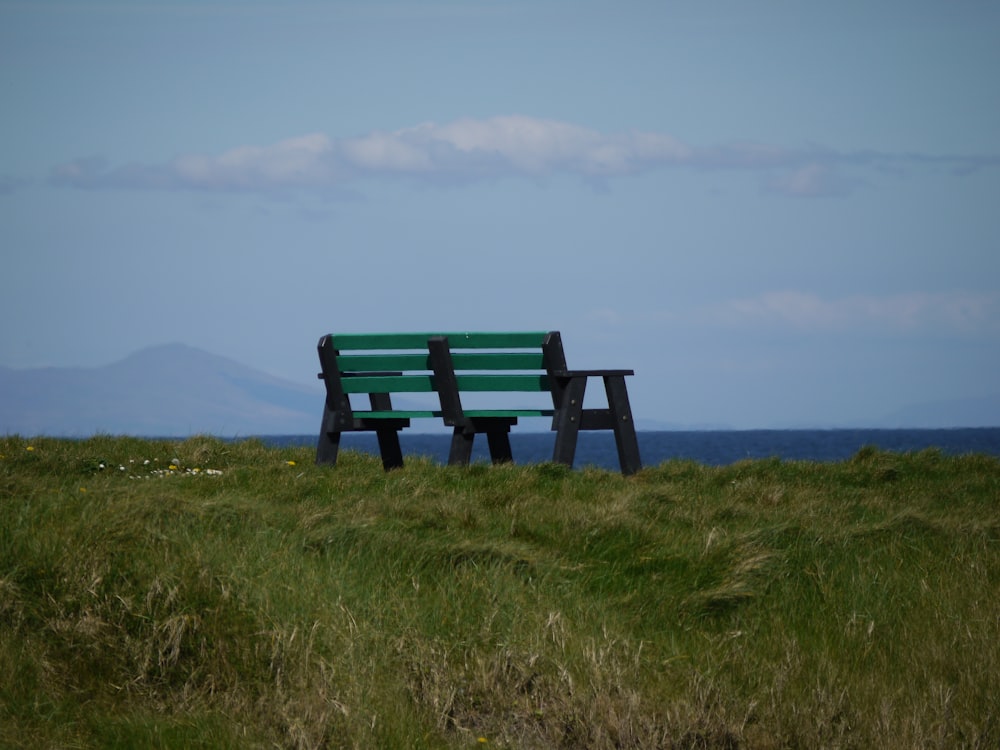 un banc vert assis au sommet d’un champ verdoyant