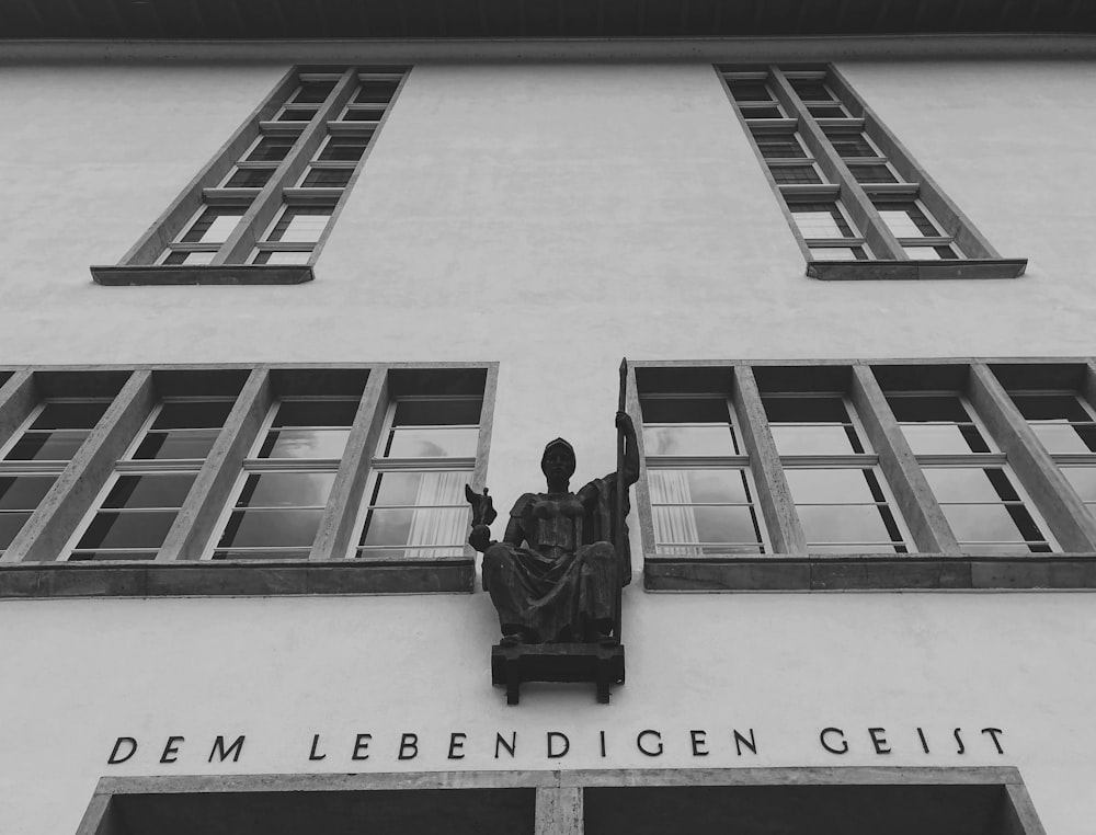a black and white photo of a statue on the side of a building