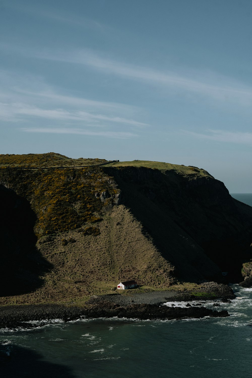 a small house on a cliff overlooking the ocean