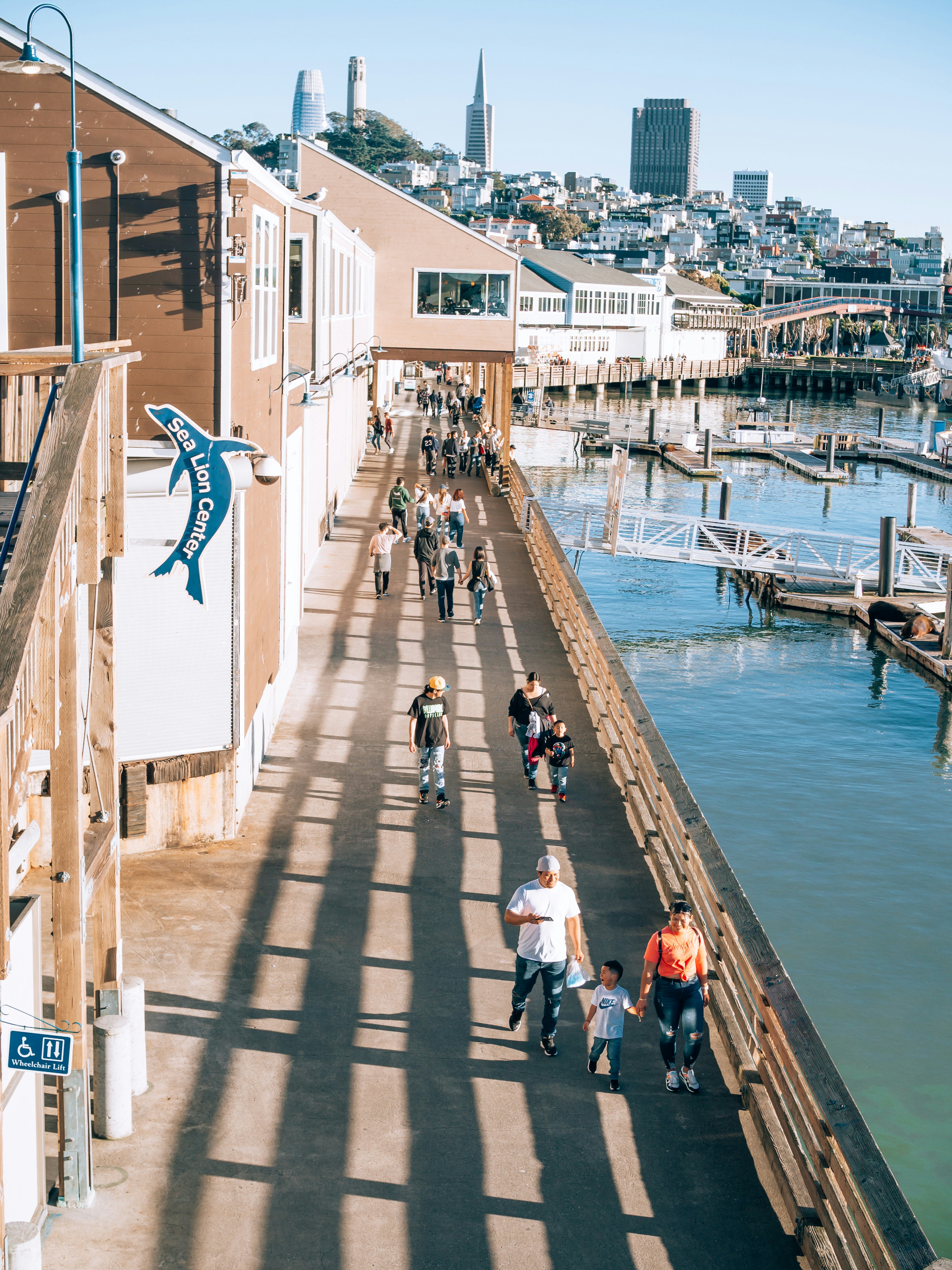 a group of people walking down a walkway next to a body of water