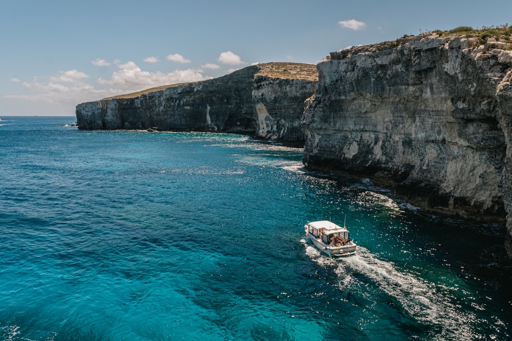 a small boat is in the water near a cliff