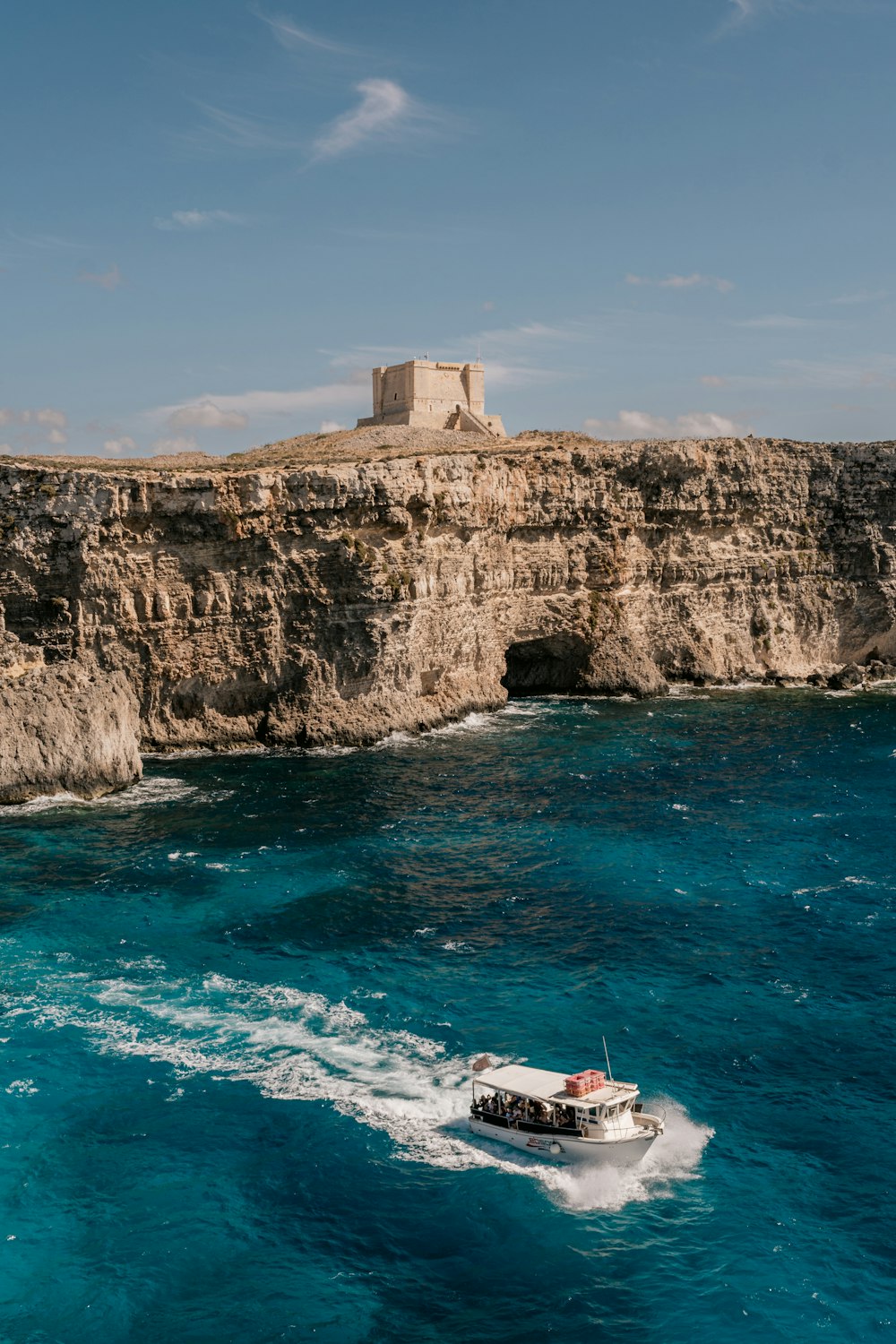 a small boat in the water near a cliff