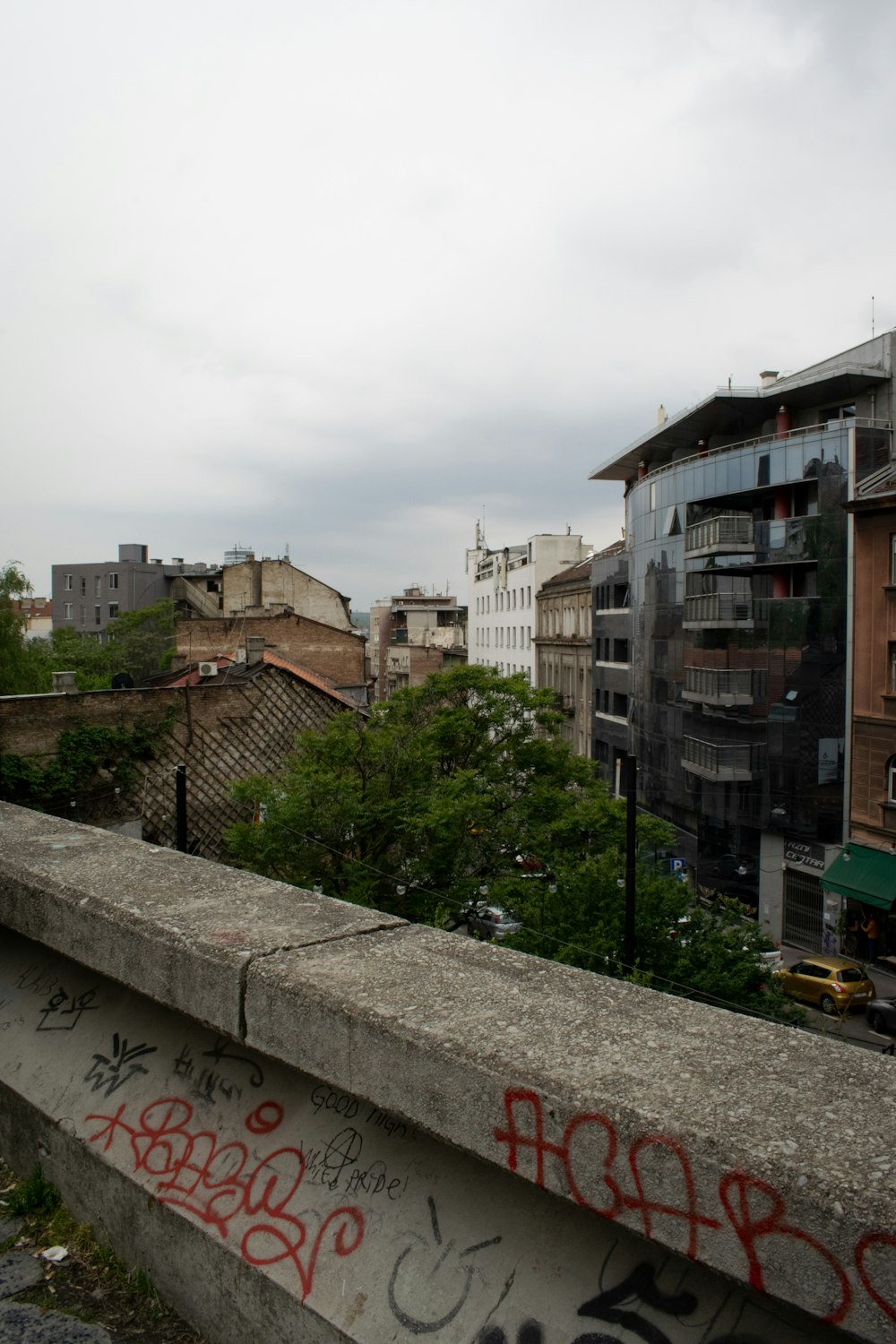 a concrete wall with graffiti on it and buildings in the background