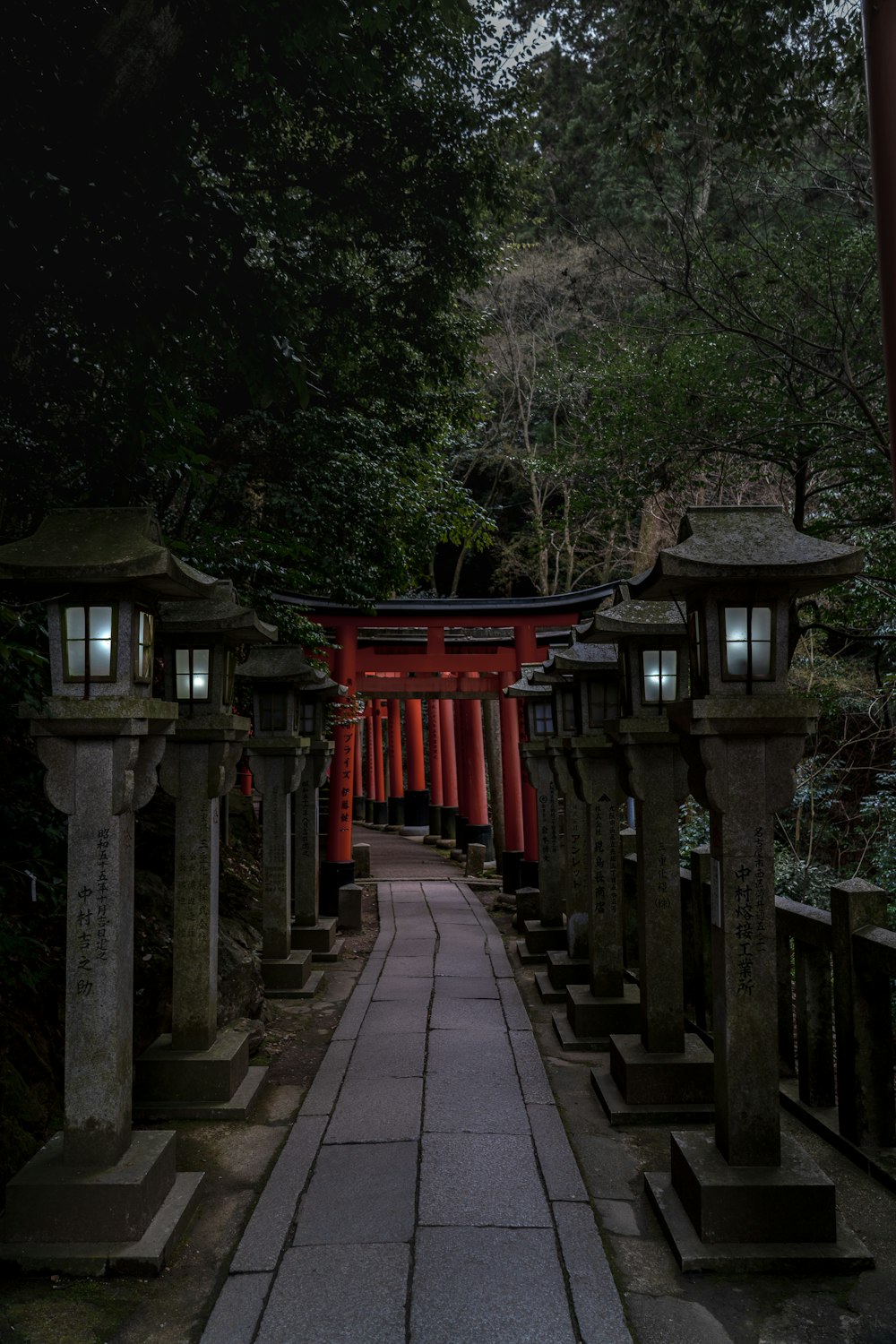 a walkway lined with lanterns in a forest