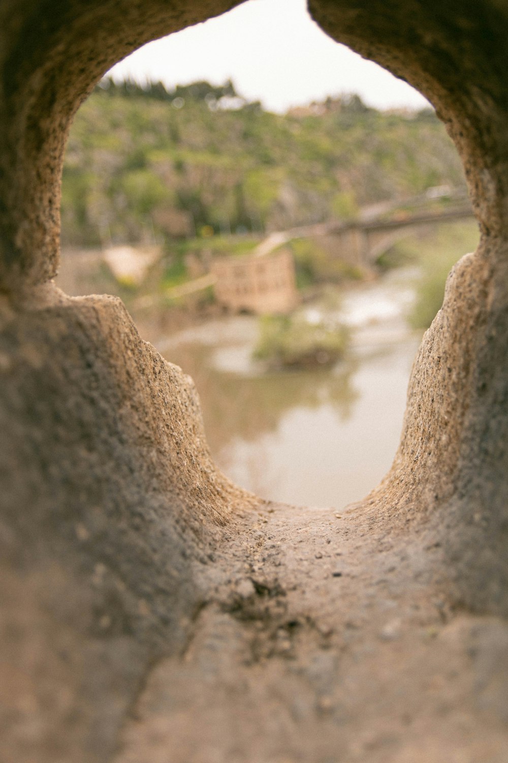 a view of a river through a hole in a stone wall