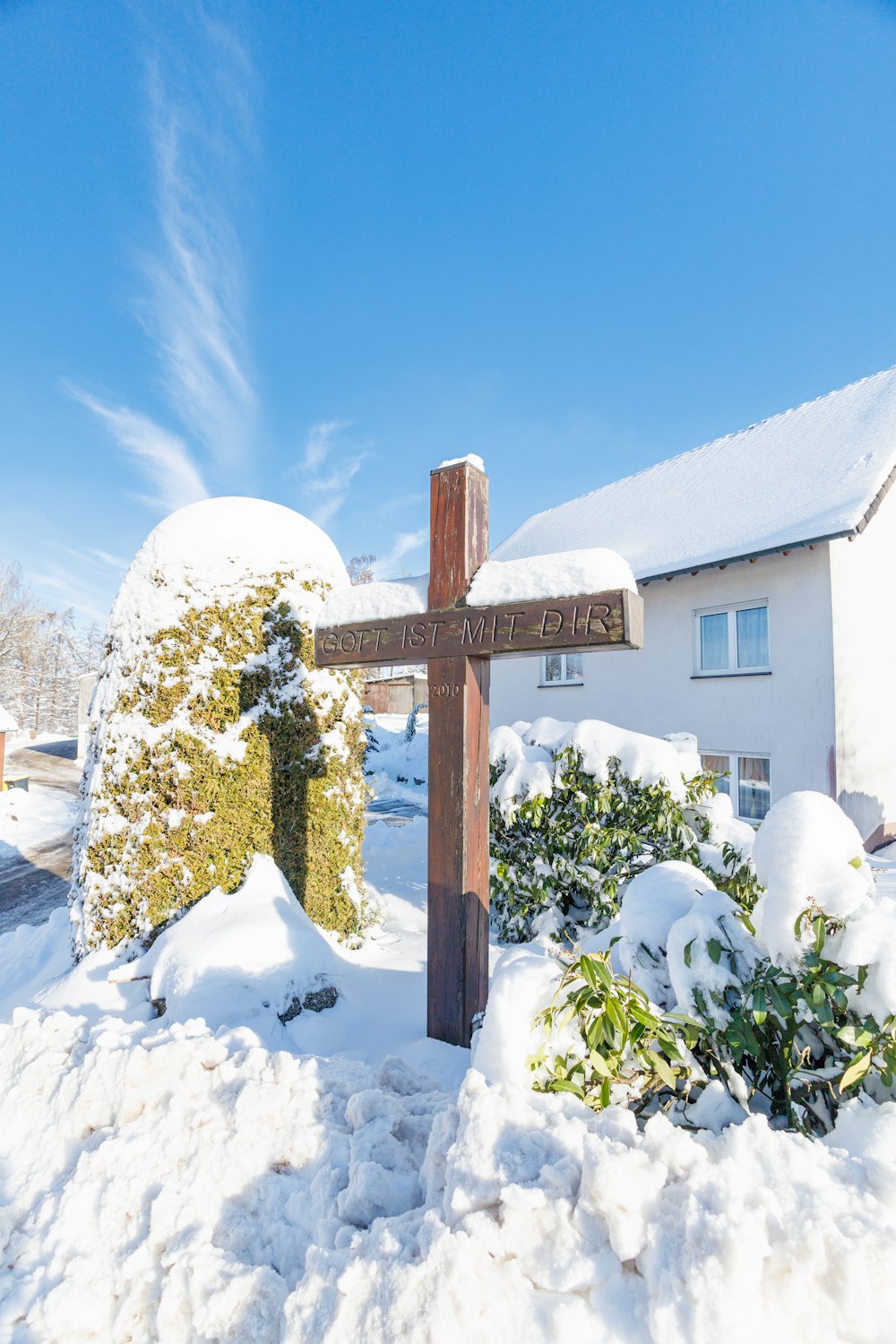 a wooden cross sitting in the middle of a snow covered yard