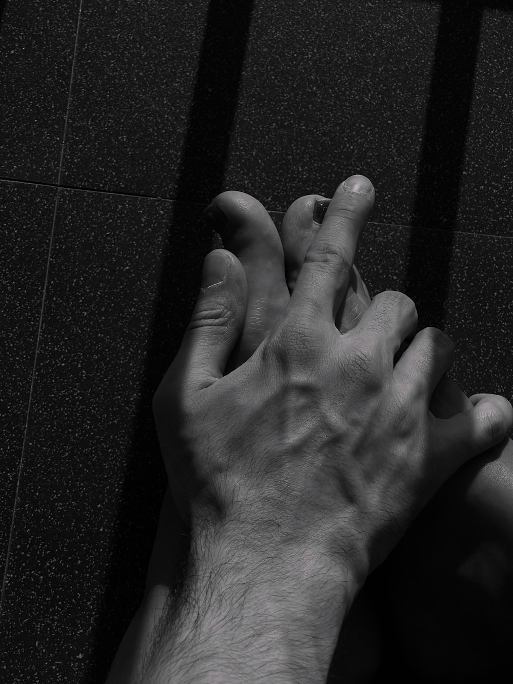 two hands reaching towards each other on a tile floor