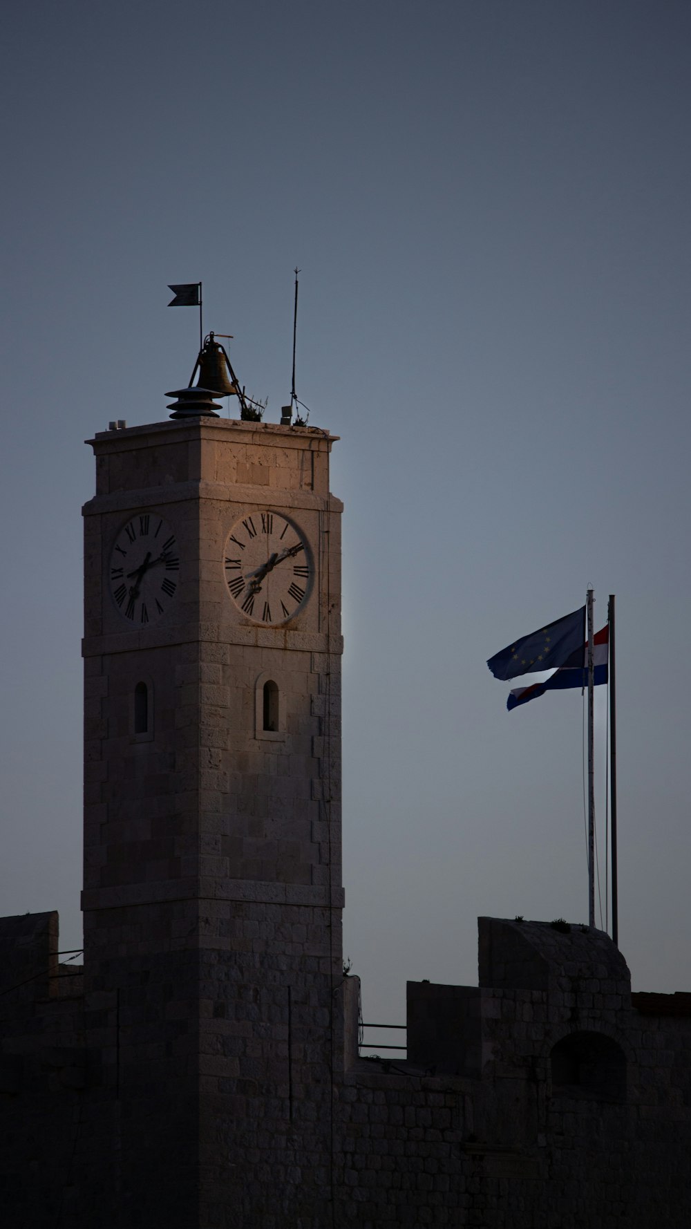 a clock tower with a flag flying next to it