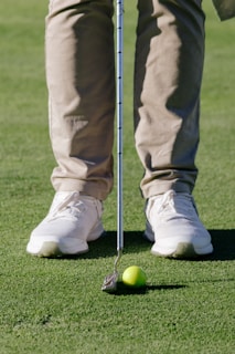 a man standing on top of a green field next to a golf ball