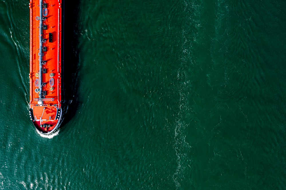 an orange boat floating on top of a body of water