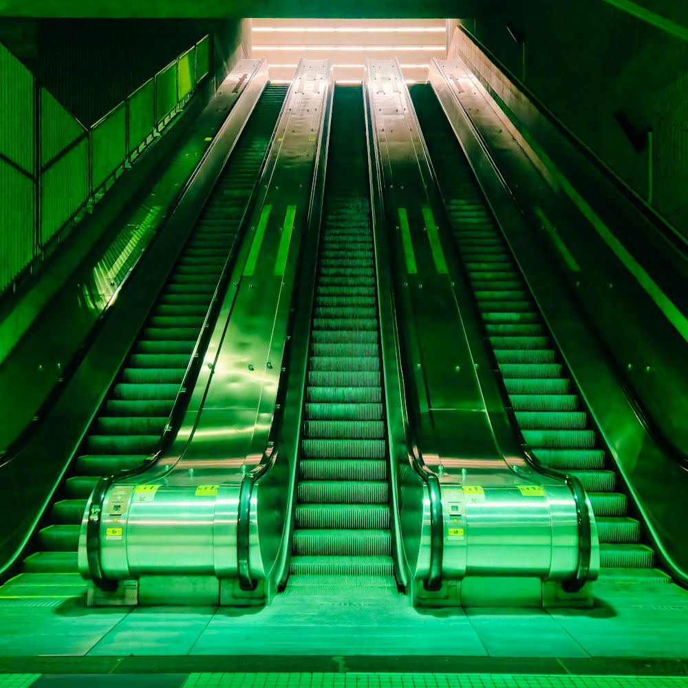 an escalator in a subway station with green lights