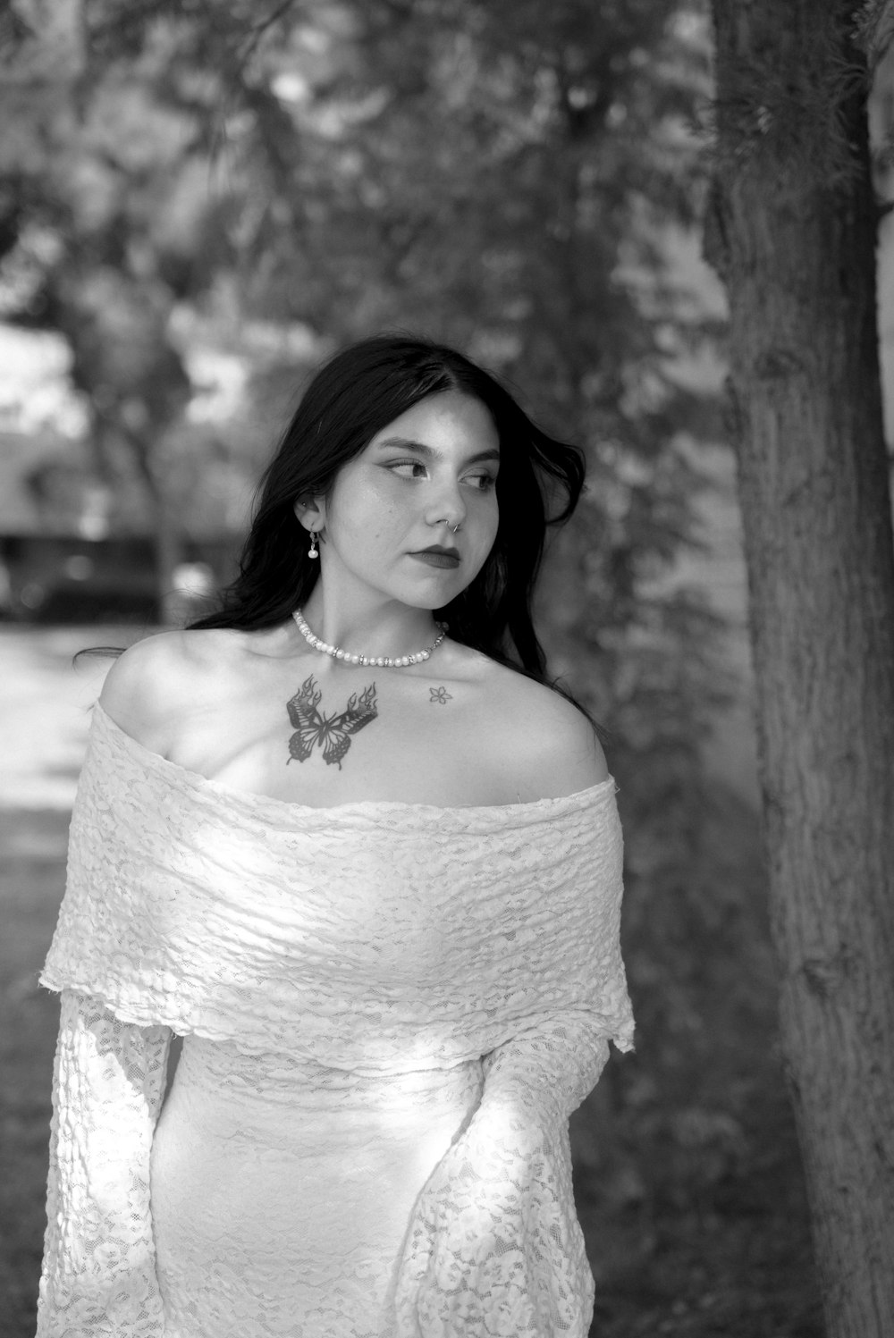 a woman in a white dress standing next to a tree