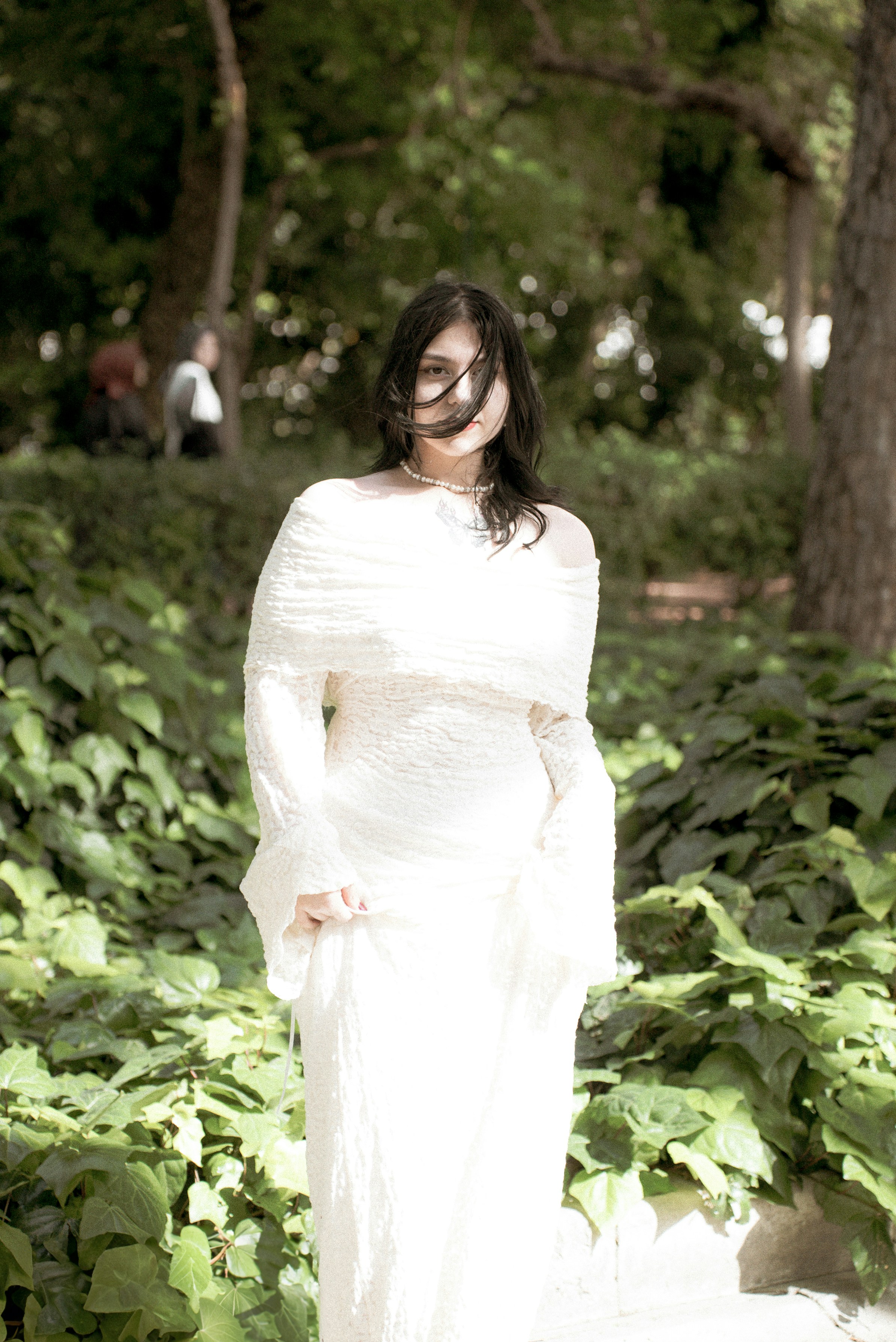 a woman in a white dress standing in a forest