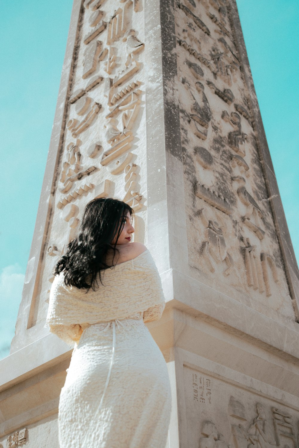 a woman in a white dress standing in front of a monument