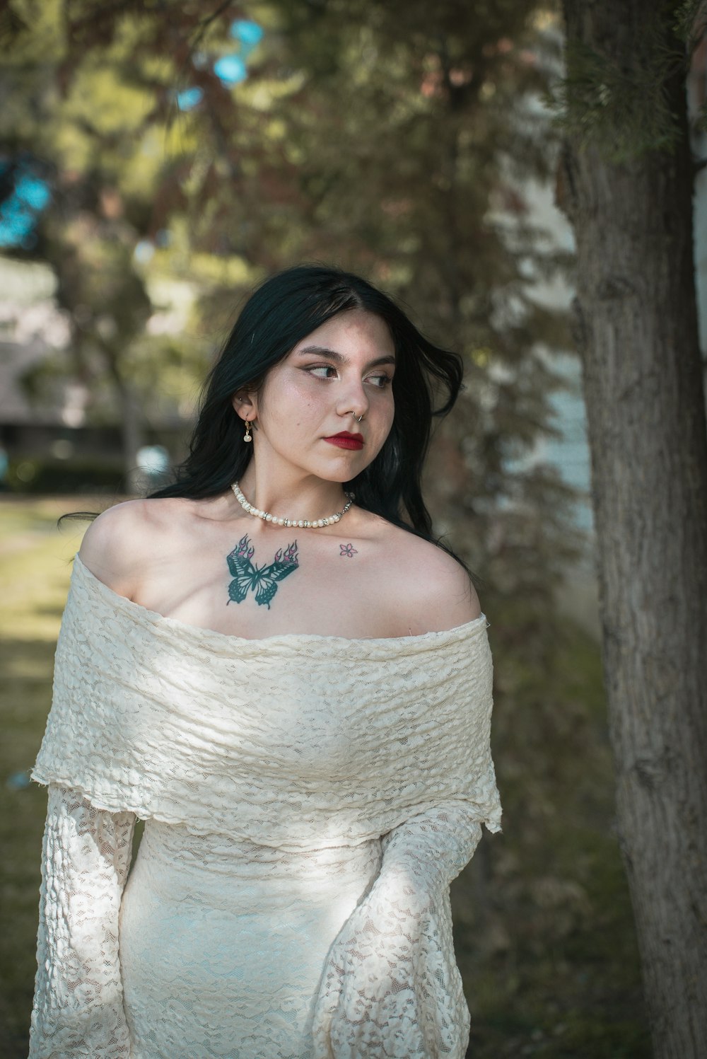 a woman in a white dress with a butterfly tattoo on her chest