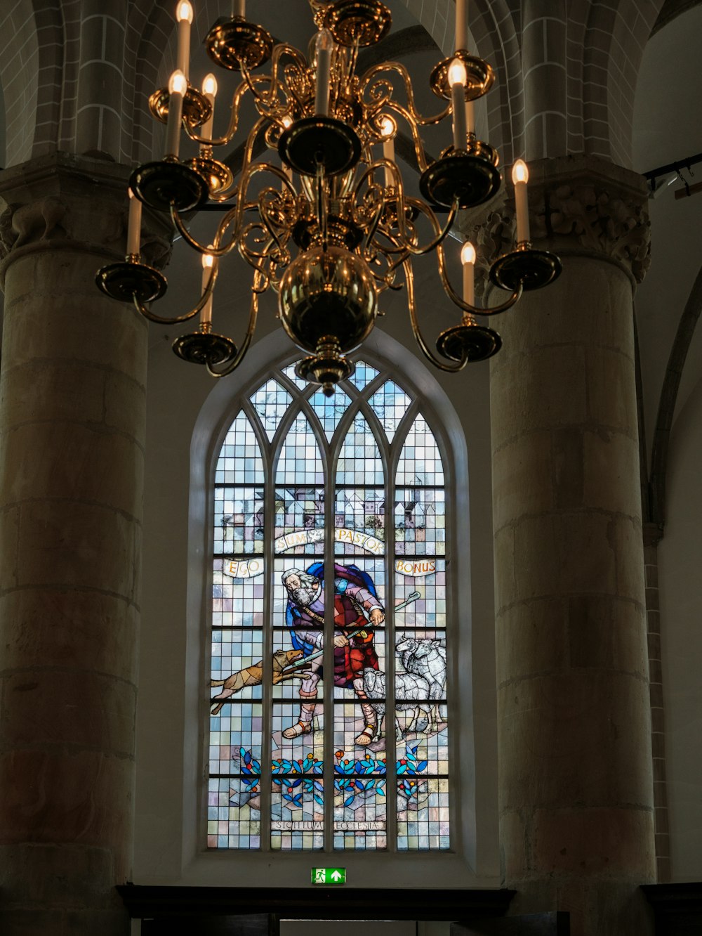 a chandelier hangs in front of a stained glass window
