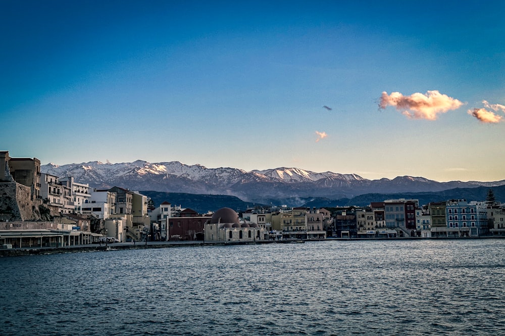 a body of water with buildings and mountains in the background