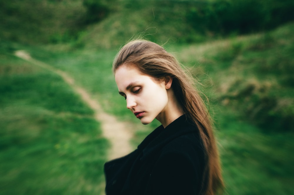 a woman with long hair standing in a field