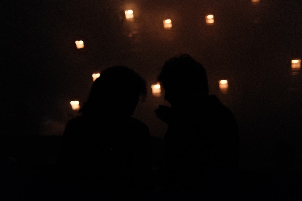 a couple of people that are standing in the dark