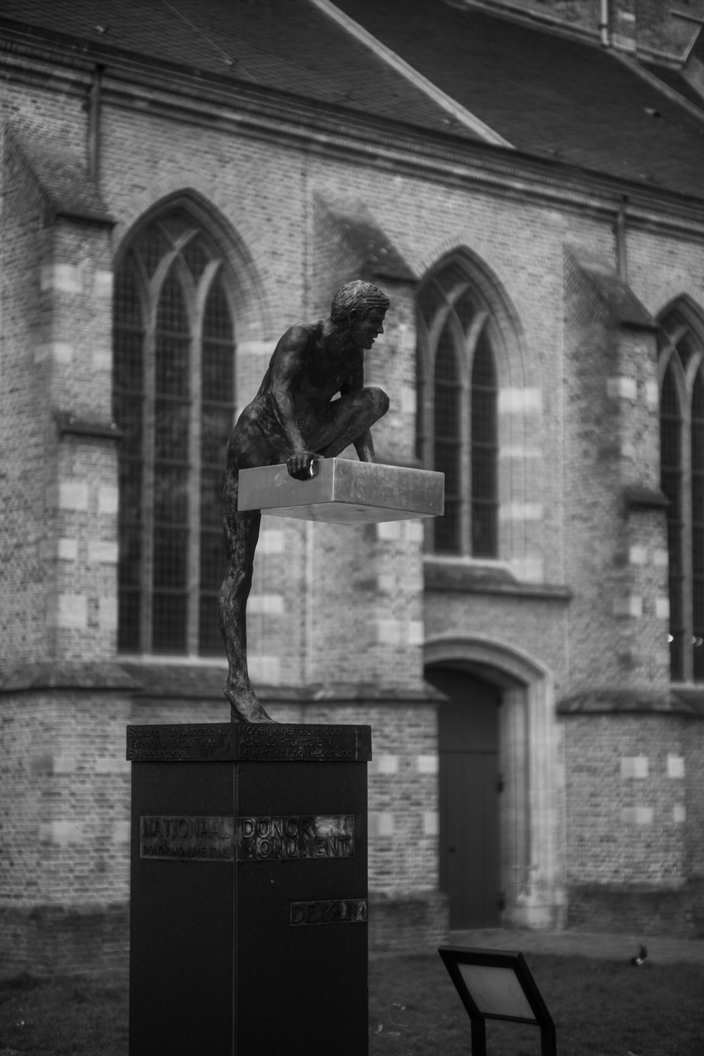 a black and white photo of a statue in front of a building