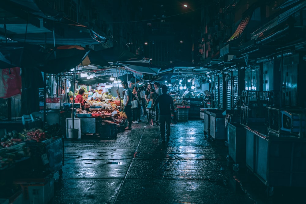 a group of people standing around a market at night
