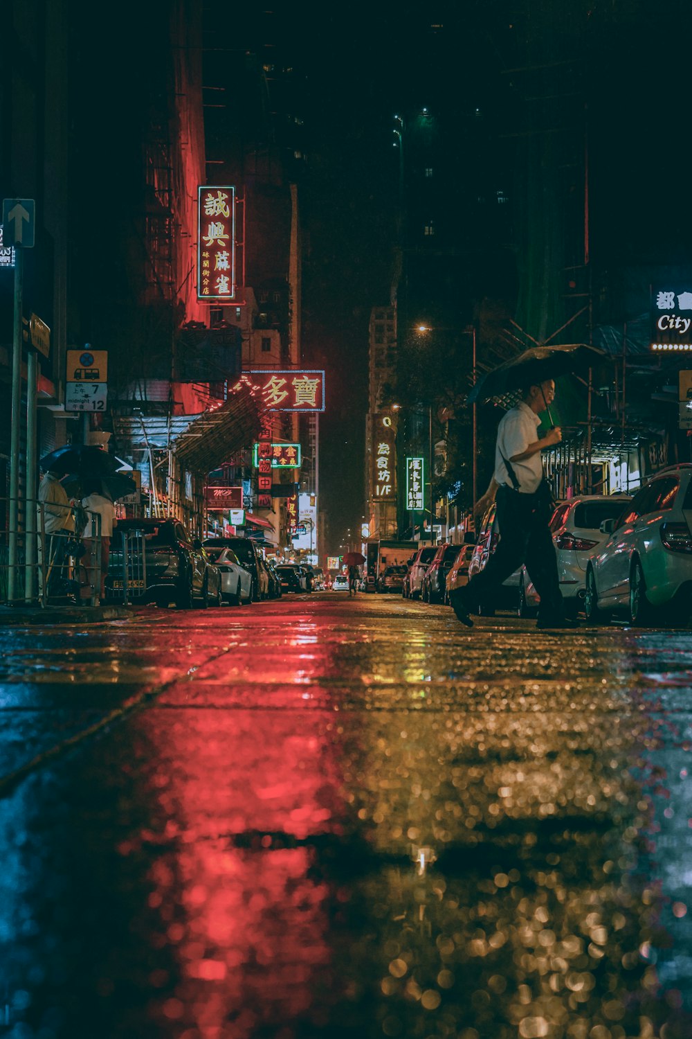 a man walking down a street at night with an umbrella