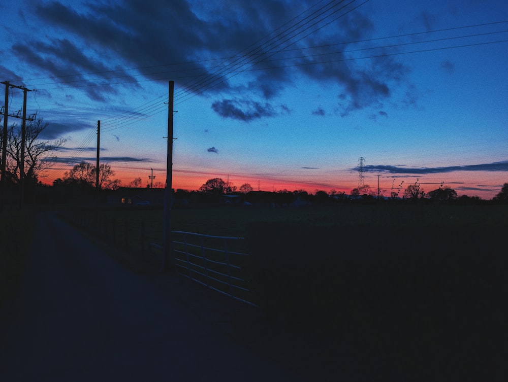 the sun is setting over a field with power lines