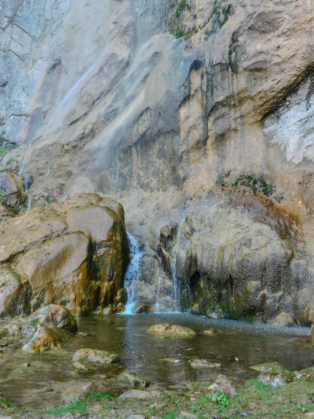 a waterfall is coming out of the rocks into the water