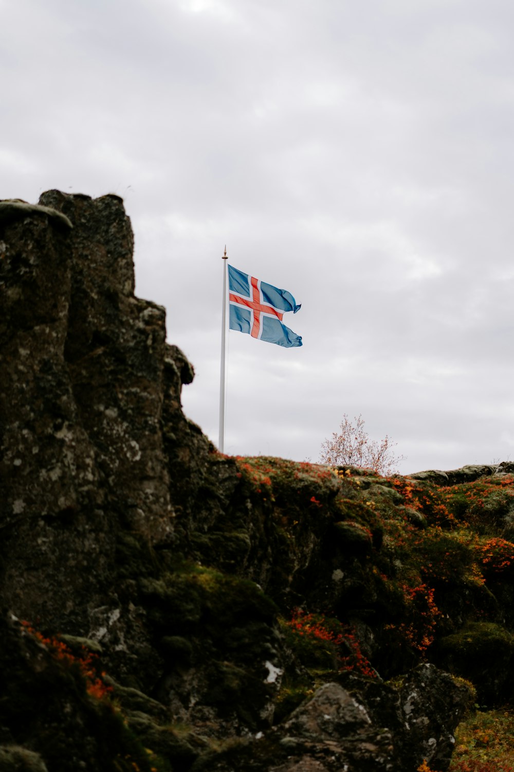 a flag flying on top of a rocky hill