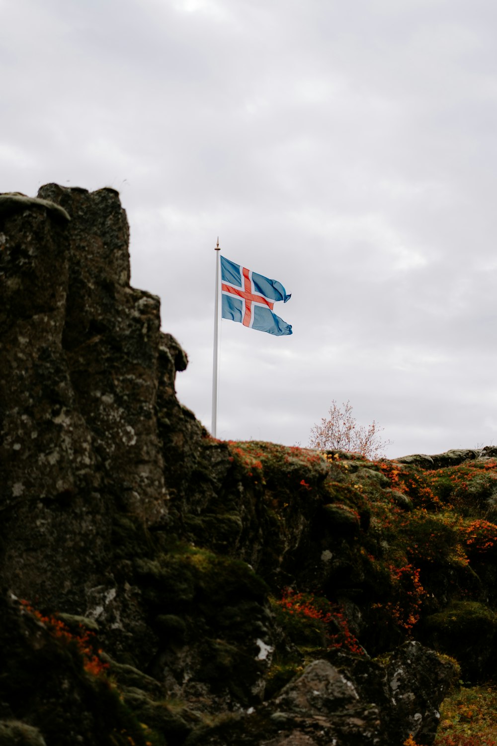 una bandera ondeando en la cima de una colina rocosa