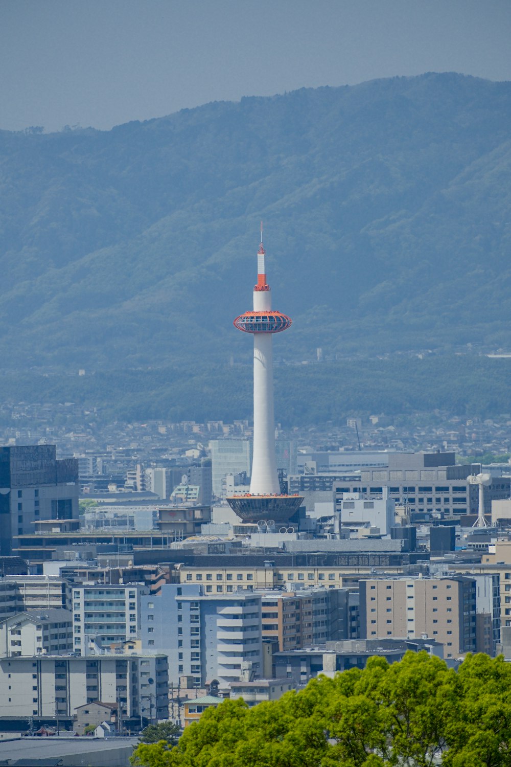 a tall white tower with a red top in the middle of a city