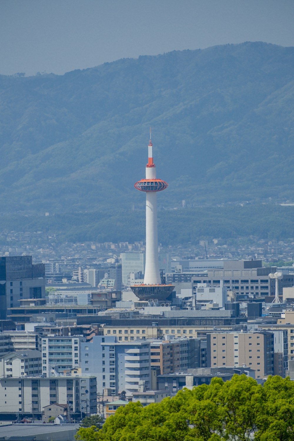 una alta torre blanca con una cima roja en medio de una ciudad