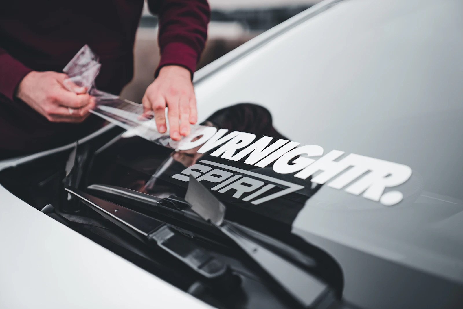 A technician hand finishing a car hood after paint work
