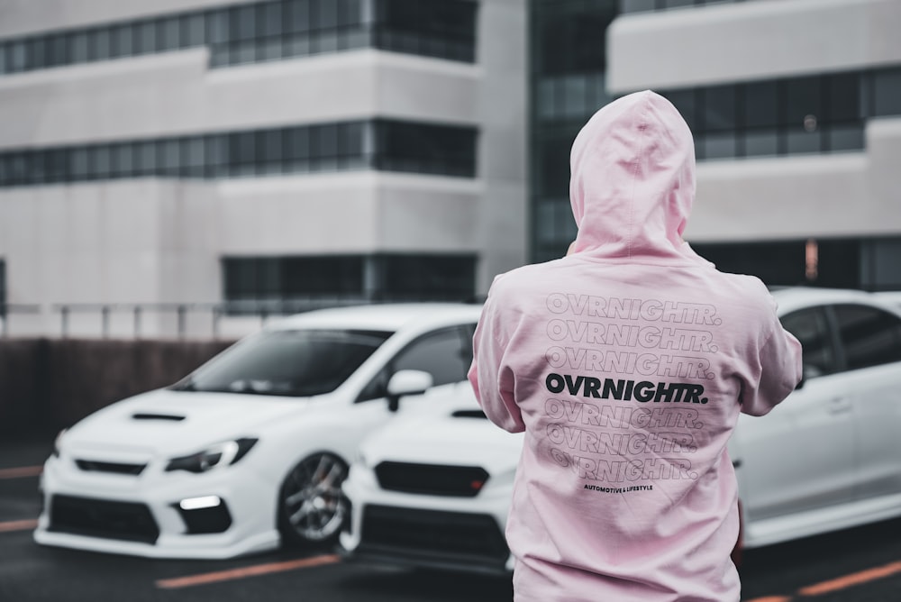 a person in a pink hoodie standing in a parking lot