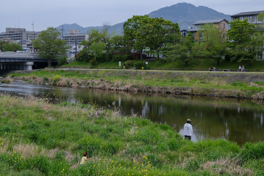 a man standing in the grass next to a river