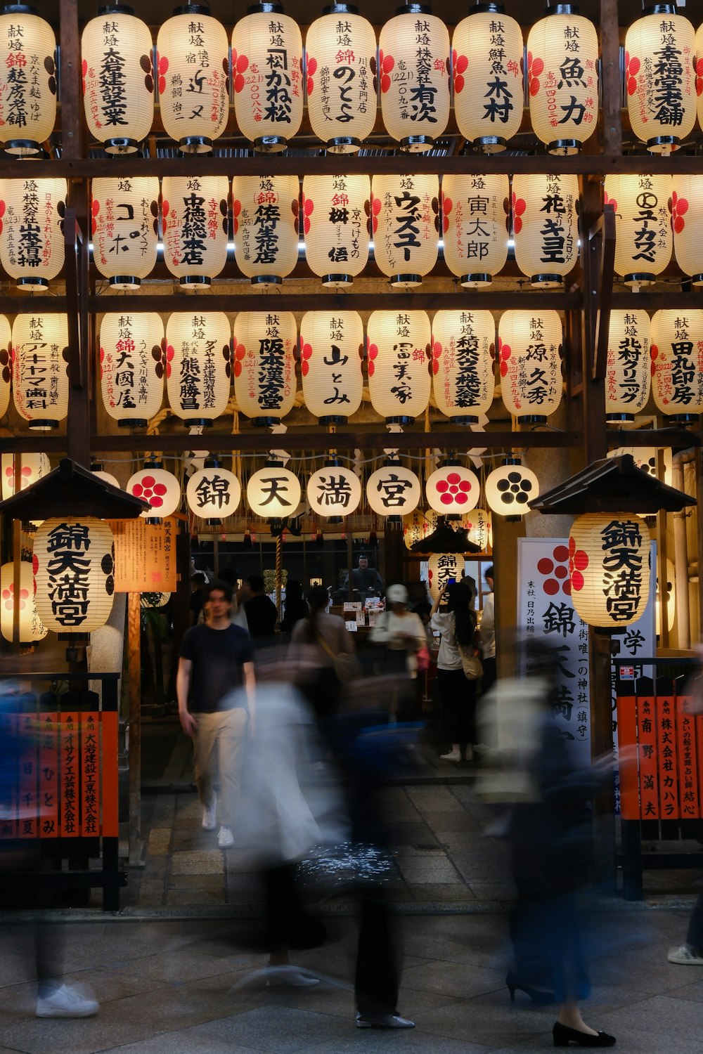 a group of people walking down a street under lanterns